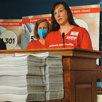 Two nurses standing at podium with stacks of paper report