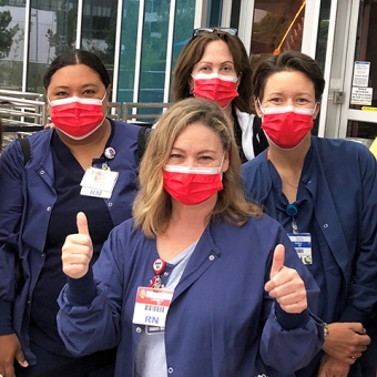 Group of nurses outside hospital with thumbs up
