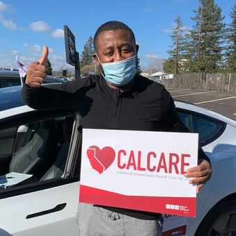 Person holding CalCare sign and giving thumbs up