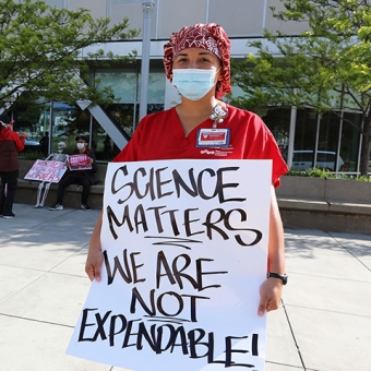Nurse holds sign "Science matters. We are not disposable."