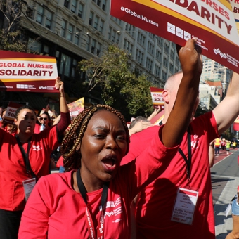 Nurses marching, holding signs "Global Nurses Solidarity"