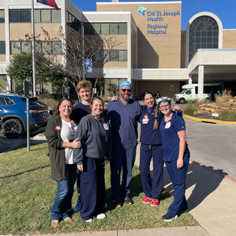 Six nurses outside hospital, smiling