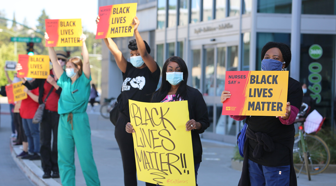 Nurses outside hospital hold signs "Black Lives Matter"