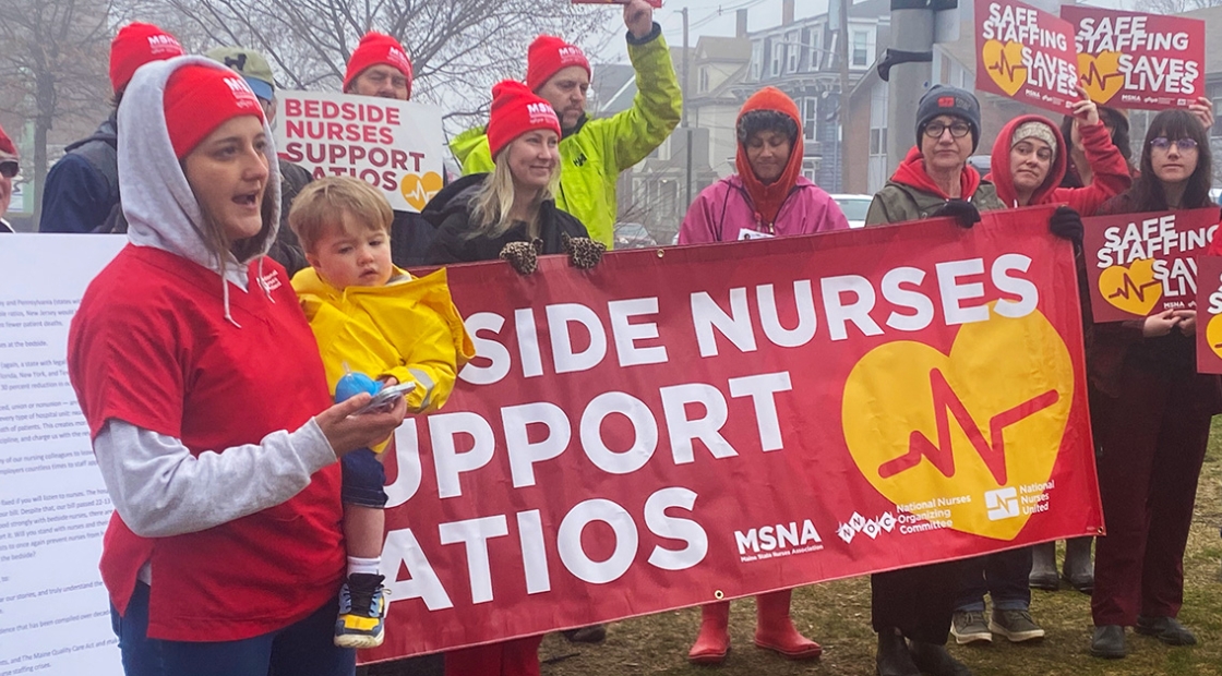 Group of nurses standing outside in cold weather holding banner "Bedside Nurses Support Ratios"