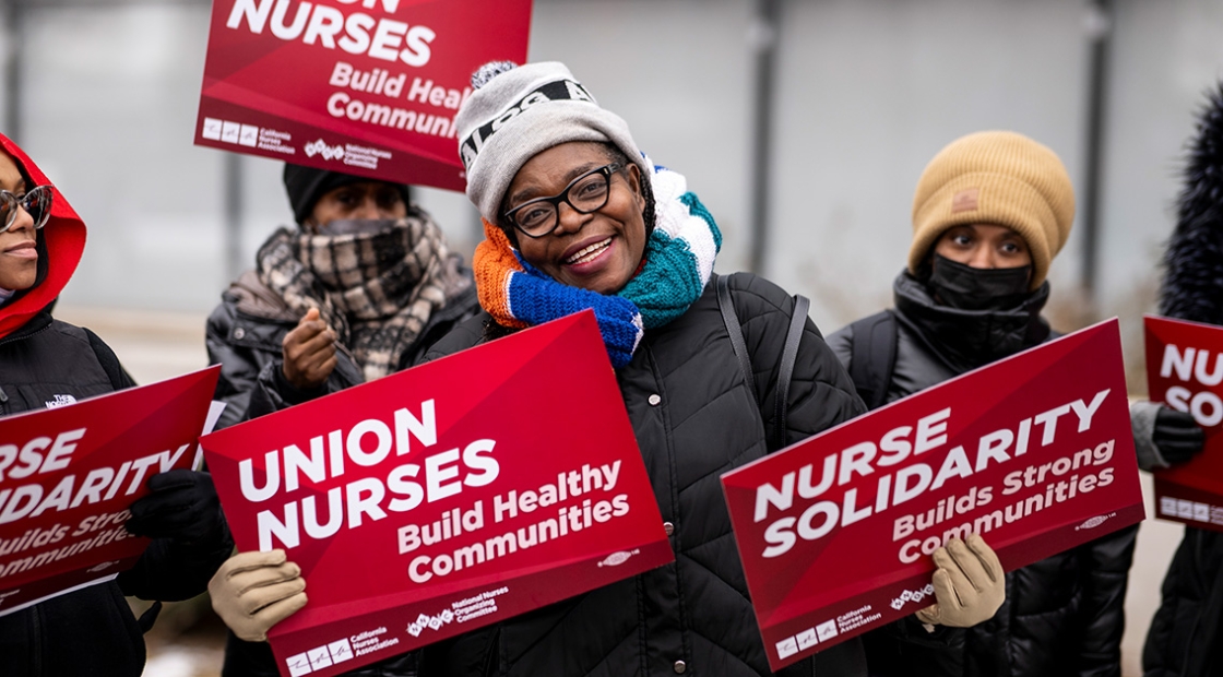 Nurses smiling, holding signs "Union Nurses Build Healthy Communities"