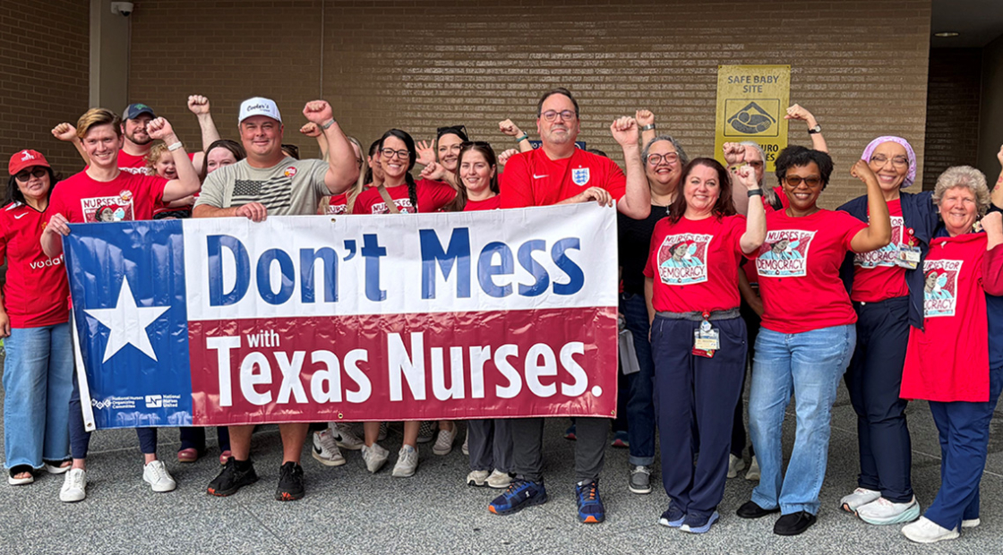 Large group of nurses outside hospital, with raised fists, holding banner "Don't Mess With Texas Nurses"