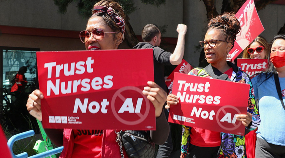 Nurses on picket line hold signs "Trust Nurses, Not A.I."