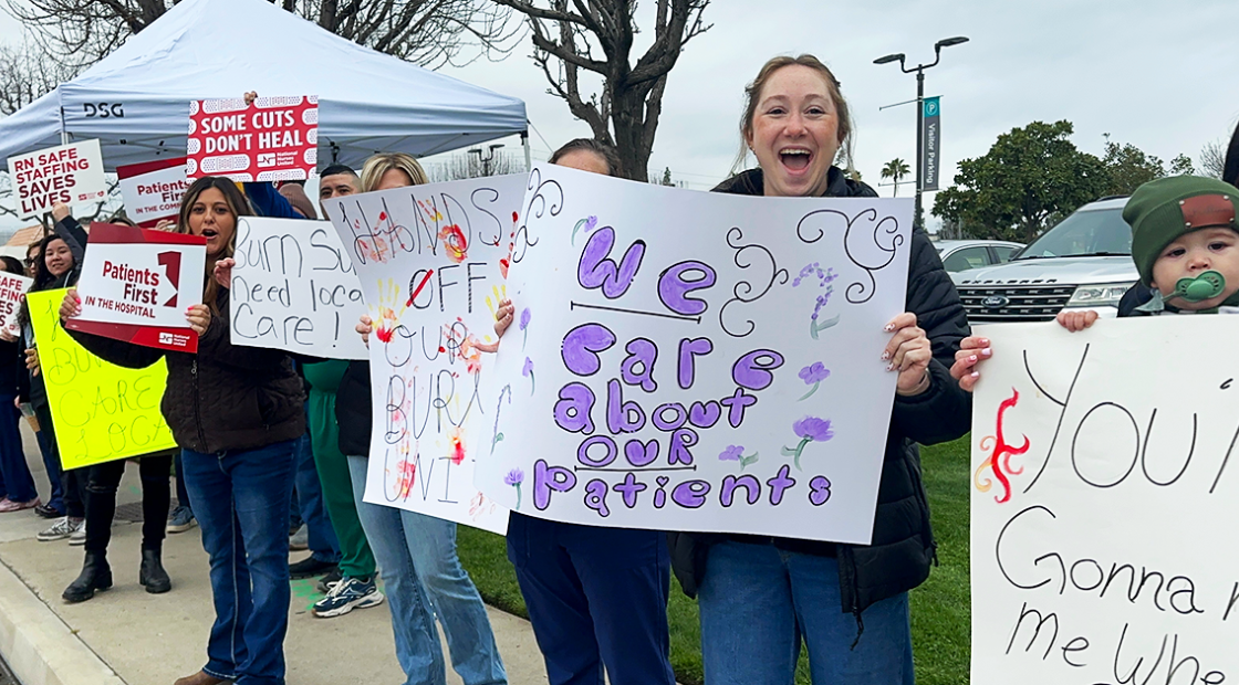 Bakersfield nurses holding signs along street "We care about our patients" "Hands off our burn unit" "Some cuts don't heal"