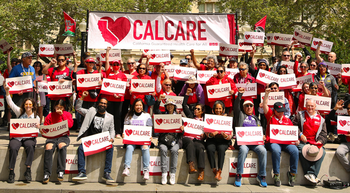 Large group of people outisde, holding CalCare signs and banner