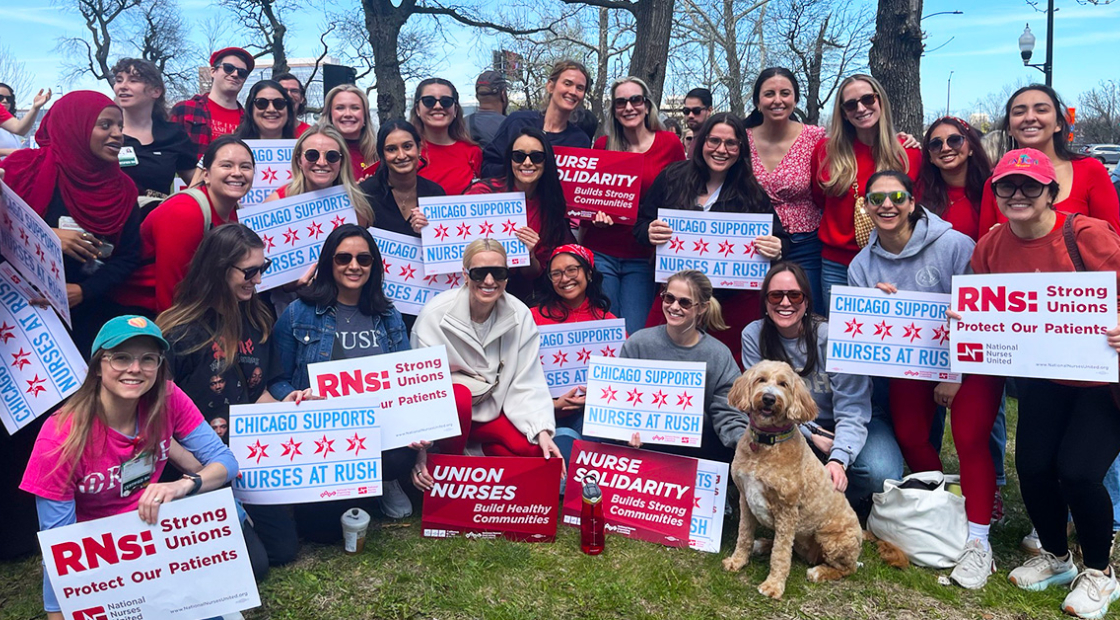 Large group of people outside, smiling, holding signs "Chicago Supports Nurses At RUSH"