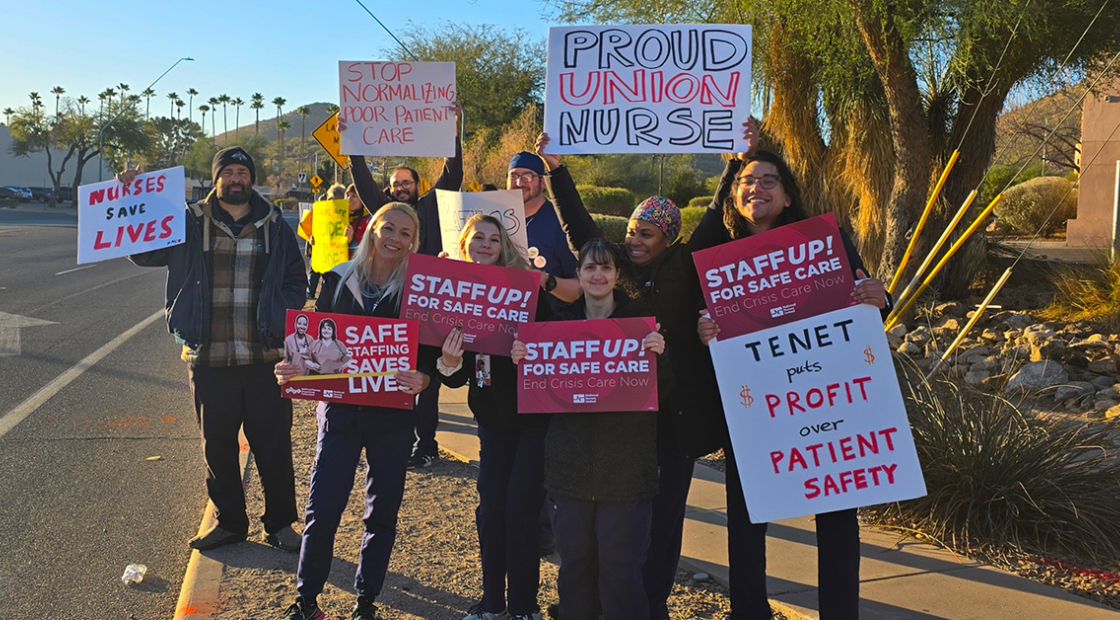 Nurses picketing on side of the road, some hold signs "Safe Staffing Saves Lives"