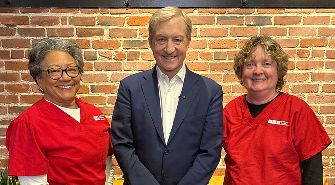 Two nurse leaders posing, smiling with Tom Steyer