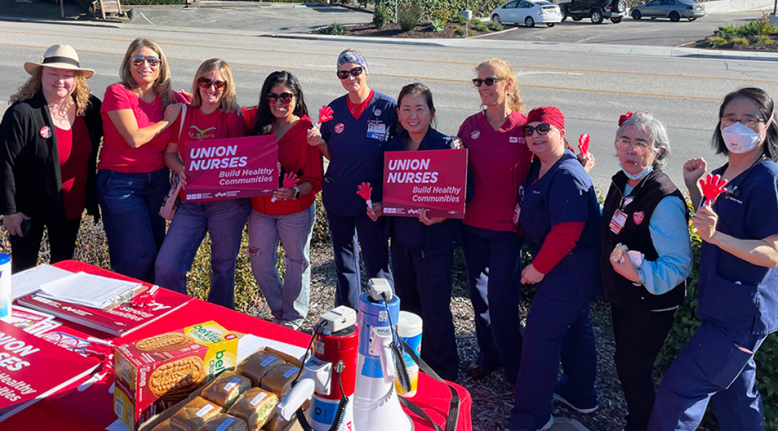 Large group of nurses outside, picketing, with signs "Union nurses build healthy communities" 