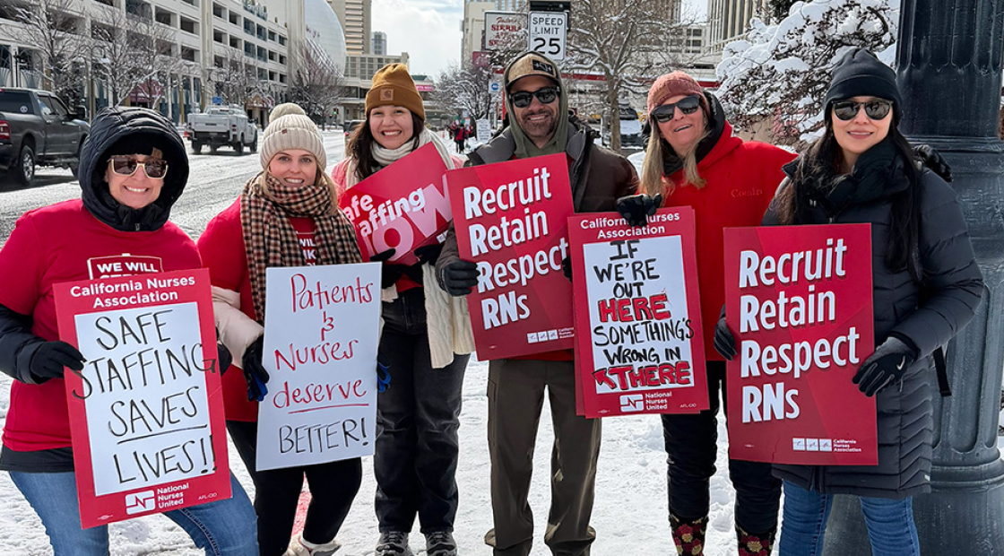 Group of nurses outside in cold weather clothes holding signs "Recruit, Retain, Respect RNs" and "Safe Staffing Saves Lives"