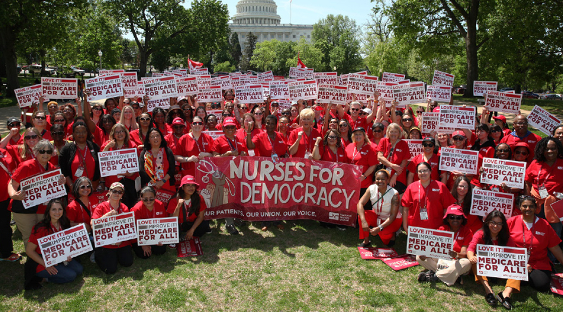 Large group of nurses in Washington D.C., holding signs "Medicare for All" and banner "Nurses for Democracy"