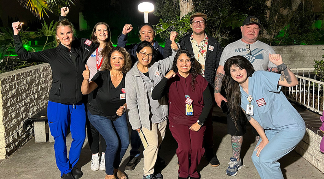 Group of nurses outside, at night, smiling, with raised fists
