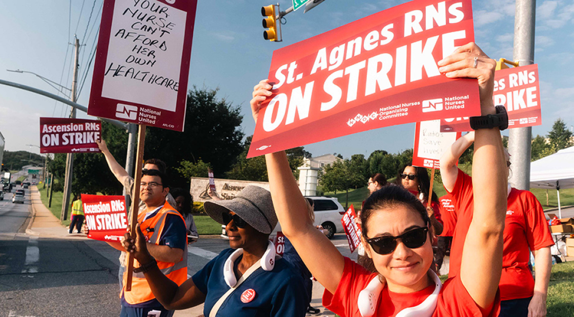 Nurse outside hospital holding sign "St. Agnes RNs ON STRIKE"