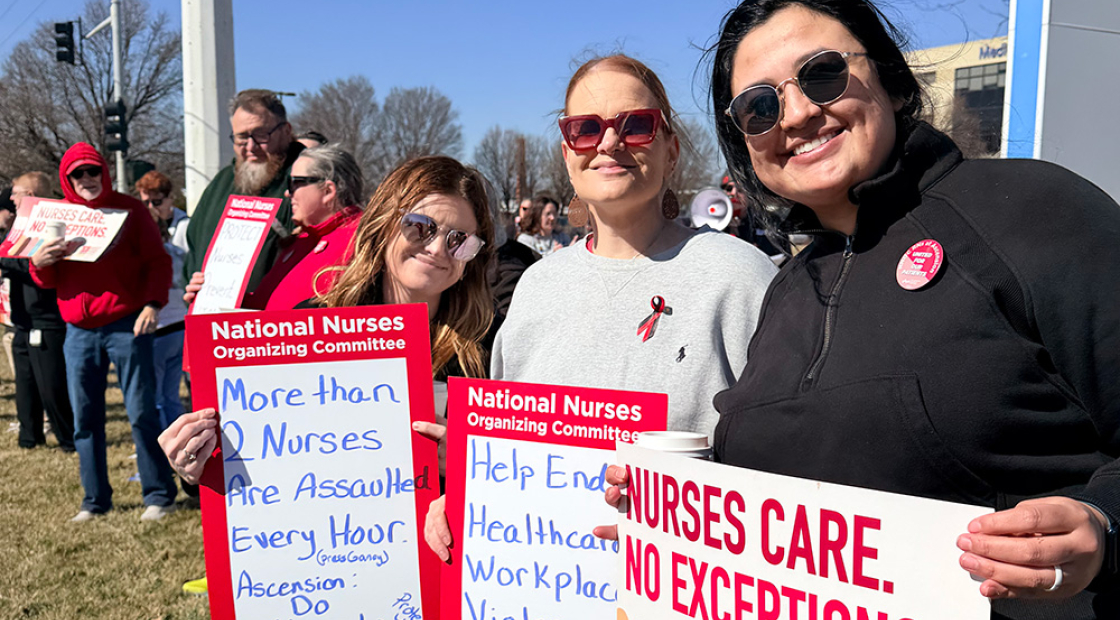 Three nurses picketing outside hospital holding signs calling for better working conditions