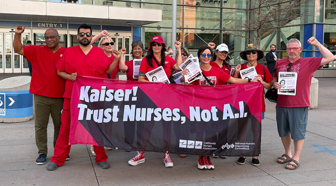 Group of nurses outside, with raised fists, holding banner "Kaiser! Trust Nurses Not A.I."