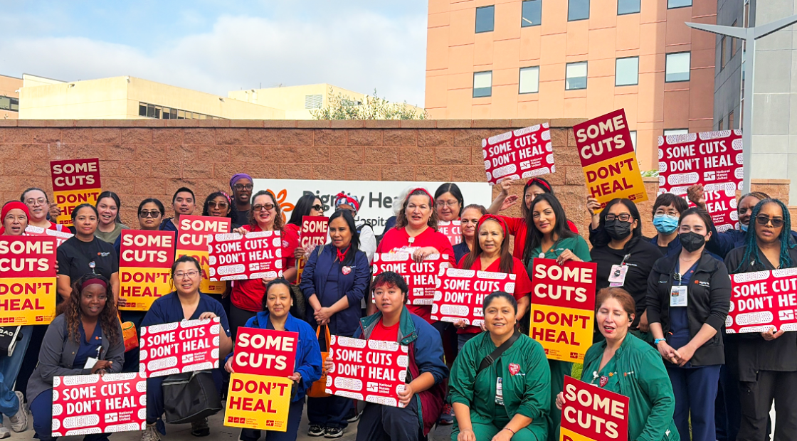 Group of CommonSpirit nurses with signs "Some Cuts Don't Heal"