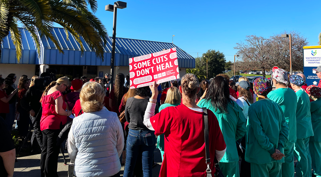 Watsonville nurse, staff, community, holding sign "Some cuts don't heal"