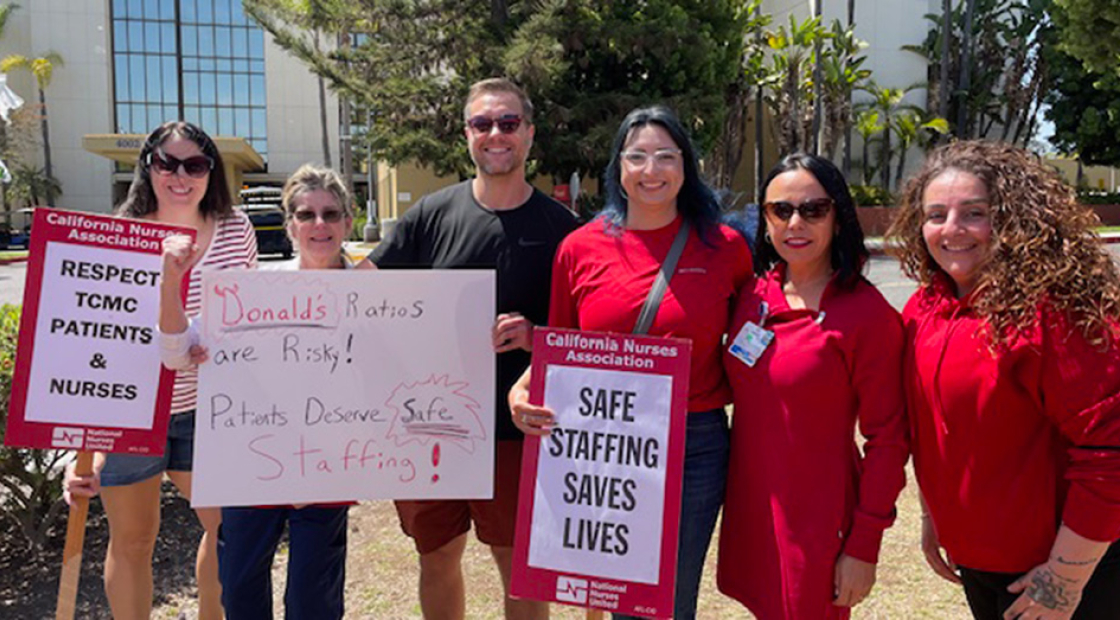 Six nurses standing outside hospital smiling, holding signs "Safe Staffing Saves Lives" and "Respect TCMC Patients and Nurses"