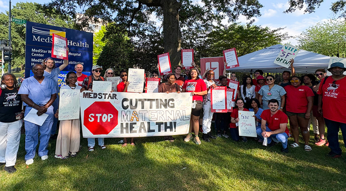 Large group of nurses and community outside hospital, holding signs and banner "MedStar: Stop Cutting Maternal Health"