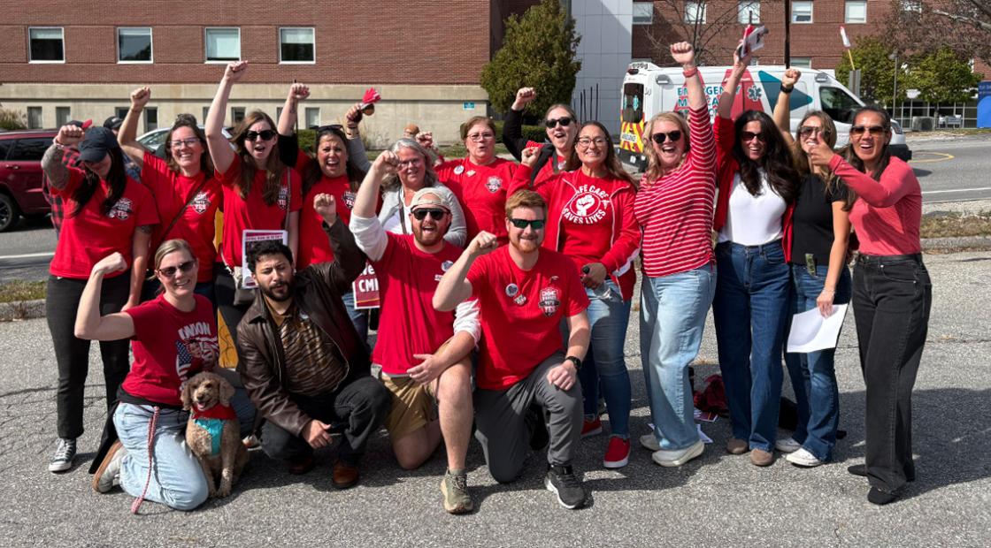 Group of nurses outside hospital, smiling, with raised fists