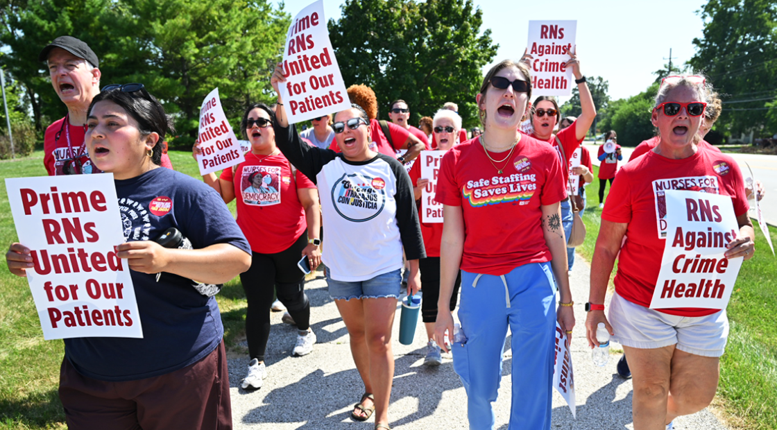 Community and nurses marching and holding signs "RNs Against Crime Health." Person with shirt "Safe Staffing Saves Lives"