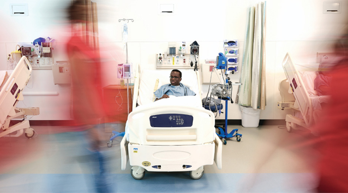 Child in hospital bed being passed by hospital staff