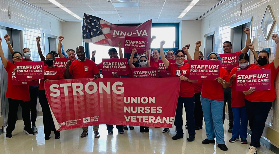 Large group of nurses inside hospital, holdig banner "Strong Union, Nurses, Veterans" and signs "Staff Up for Safe Care"