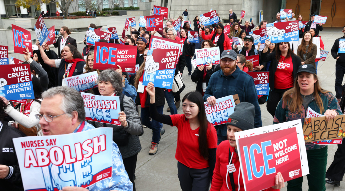 Nurses marching holding signs "ICE Not Welcome Here"