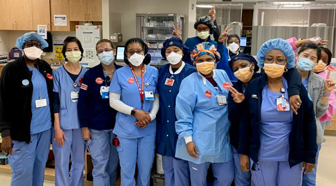 Group of nurses standing side-by-side, in hospital, smiling