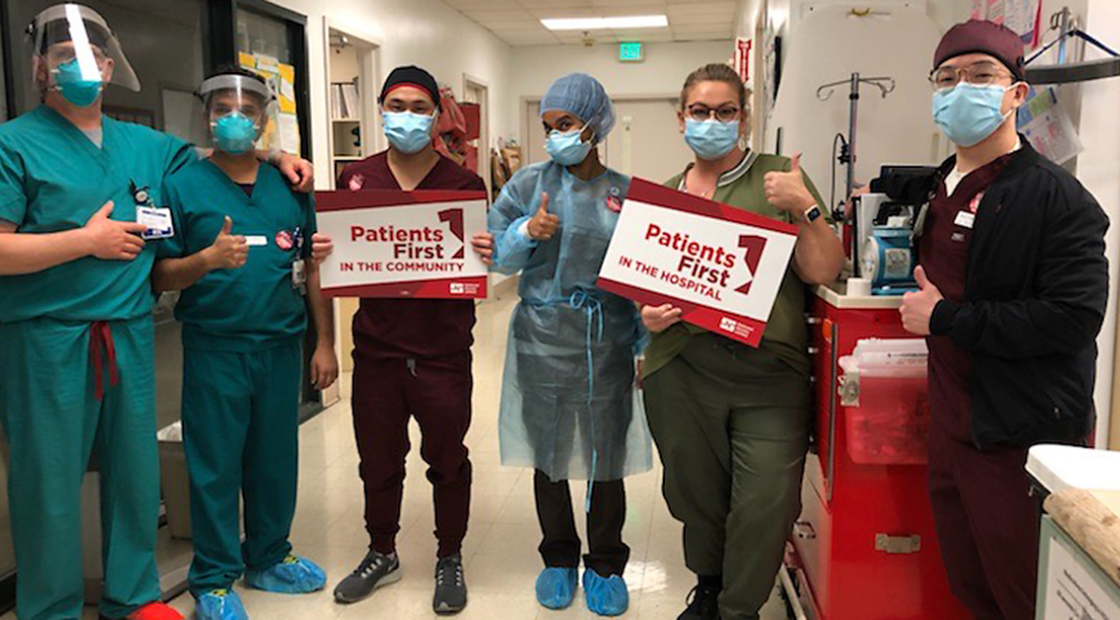 Nurses in hallway holding signs "Patients First in the Community" "Patients First in the Hospital"