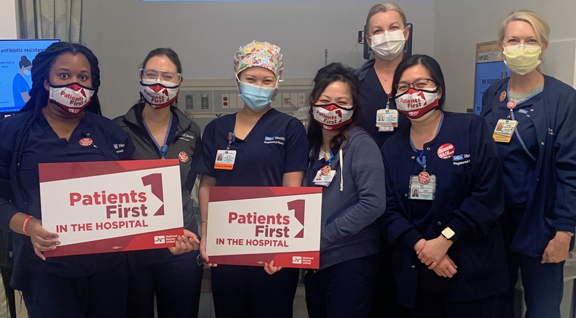 Group of nurses inside hospital hold signs "Patients First in the Hospital"