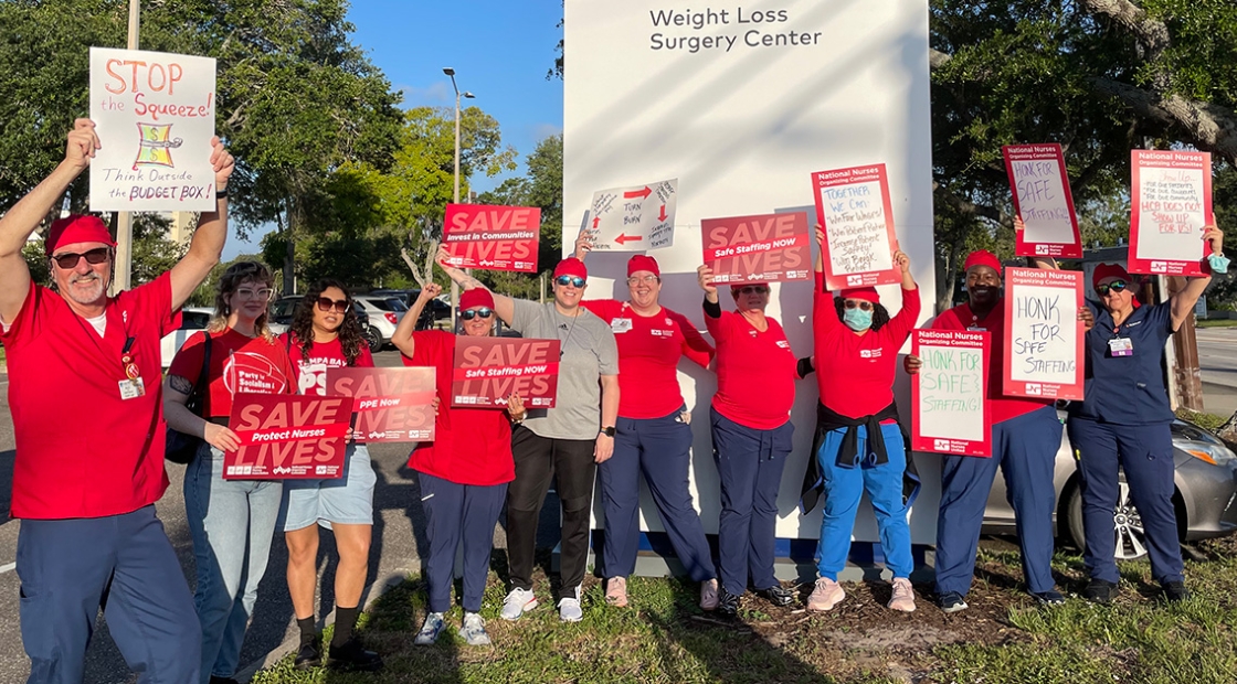 Large group of nurses outside HCA Florida Largo Hospital hold signs calling for safe staffing and other protections