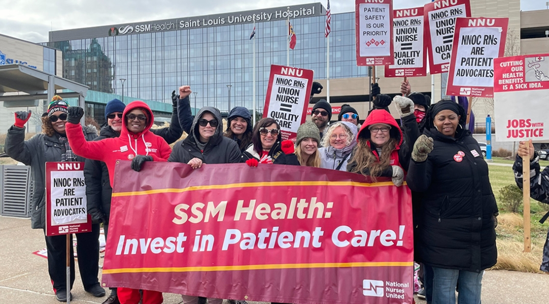 Group of nurses outside Saint Louis University Hospital holding banner "SSM Health: Invest in Patient Care!"