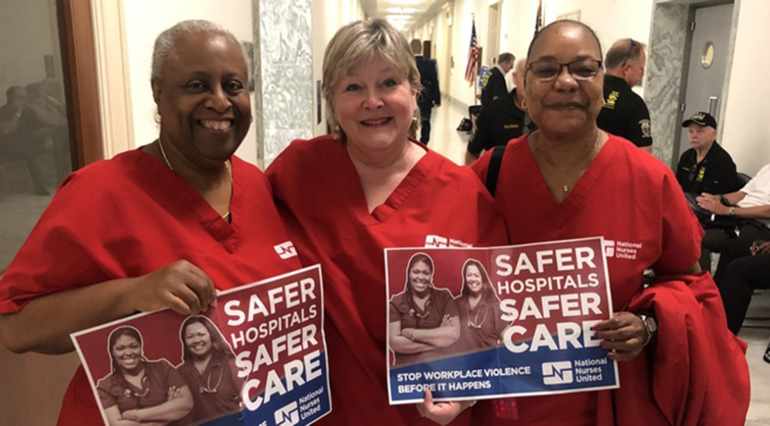 Nurses in DC government hallway with signs "Safer hospitals safer care. Stop workplace violence before it happens"