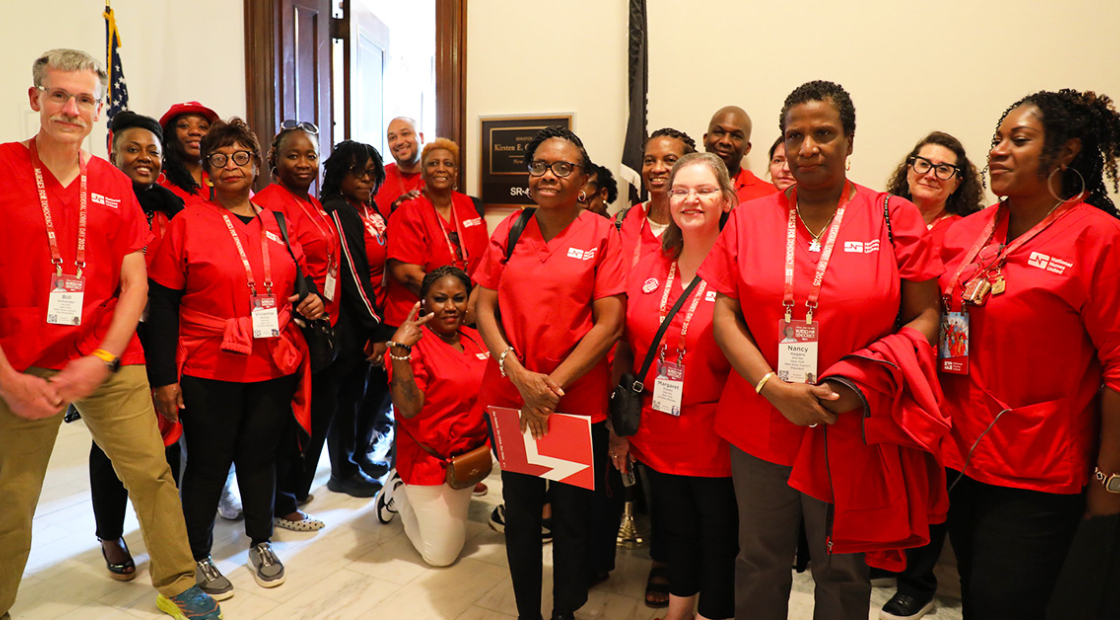 Group of nurses in red scrubs outside congressional office