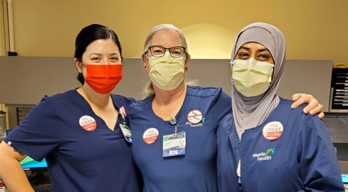 Three nurses inside hospital with arms around each other