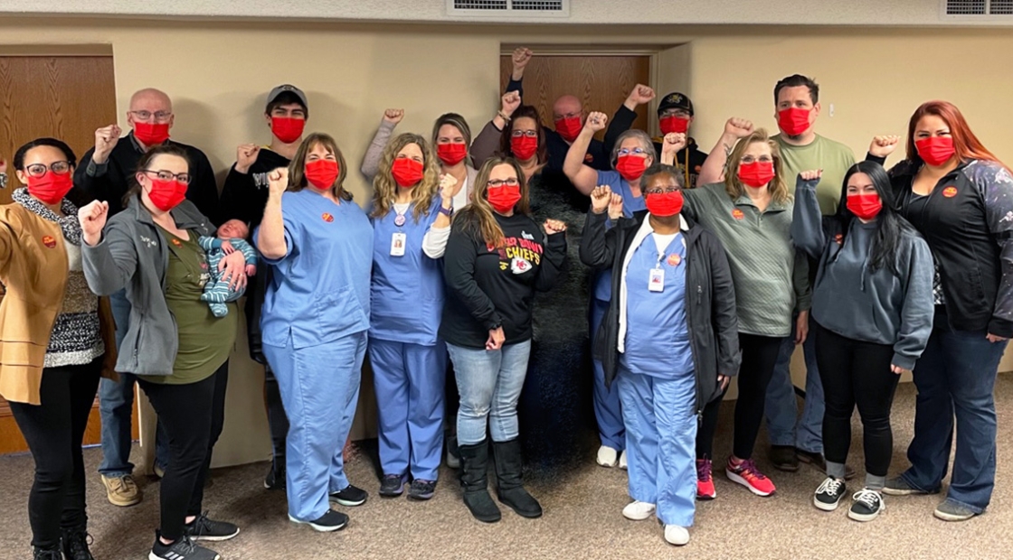 Large group of nurses inside hospital with raised fists