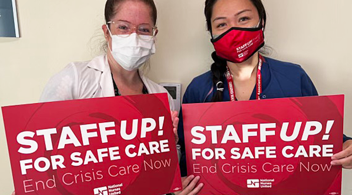Two City of Hope medical staff holding signs "Staff up! For safe care. End Crisis Care Now"