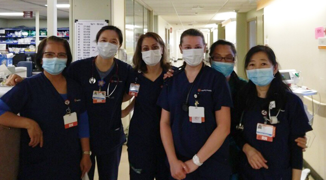Group of six nurses arm-in-arm in hospital hallway
