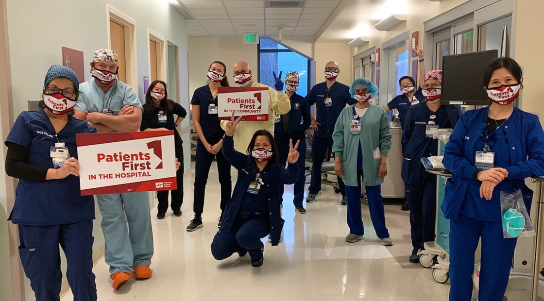 Large group of nurses in hospital hallway, two hold signs "Patients First"