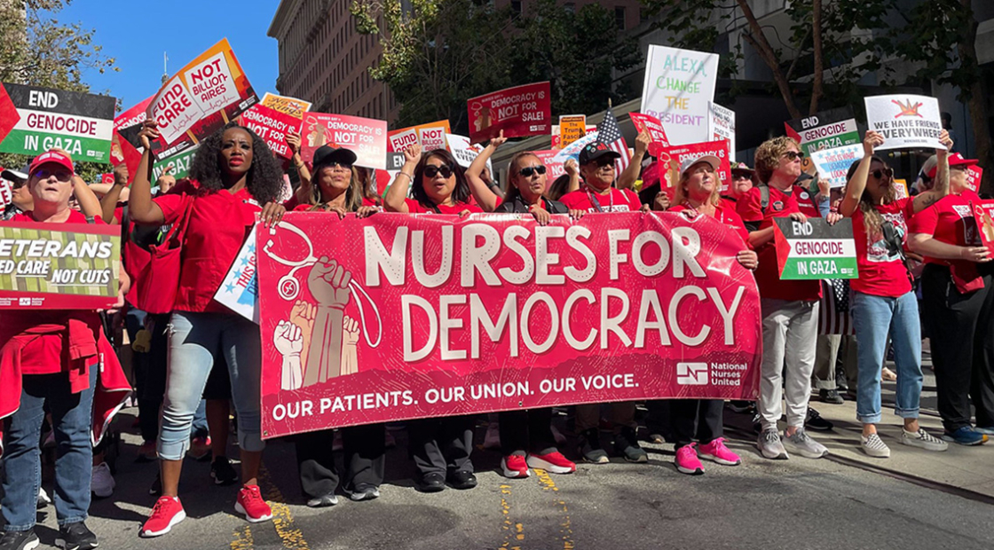 Nurse marching in street holding banner "Nurses for Democracy"