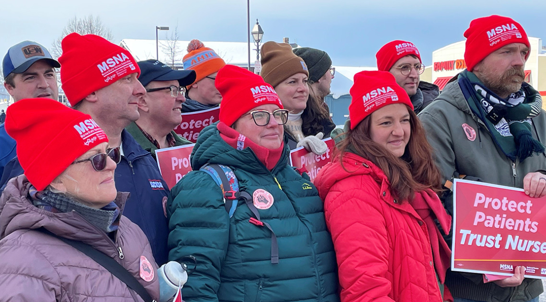 Group of nurses outside, in cold weather clothibg, wearing MSNA beanies, holding signs "Protect Patients, Trust Nurses"