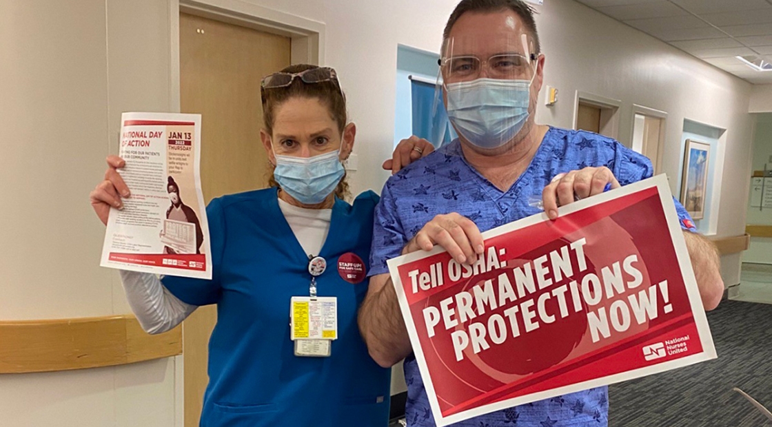 Two nurses inside hospital hold signs calling for permanent ETS
