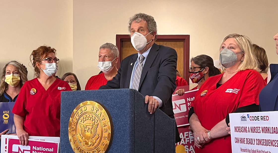 U.S. Senator Sherrod Brown at podium with nurses by his side