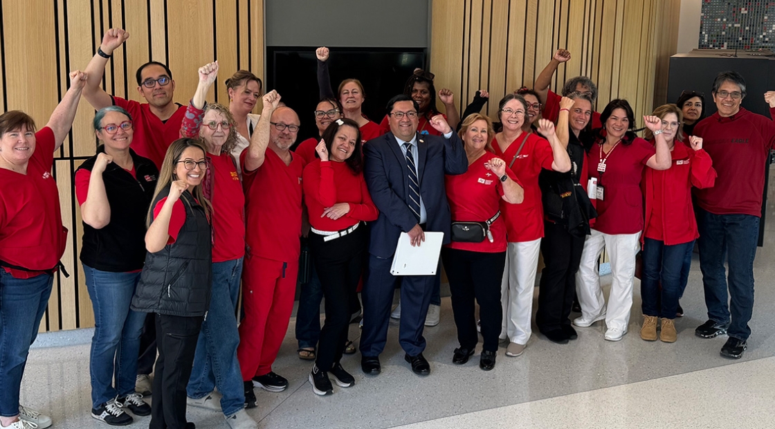 Large group of nurses with Sen. Arreguín inside, smiling, raised fists