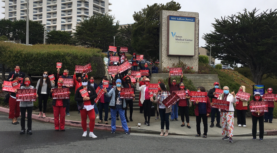 RNs on the street in front of hospital holding signs "Save Lives'